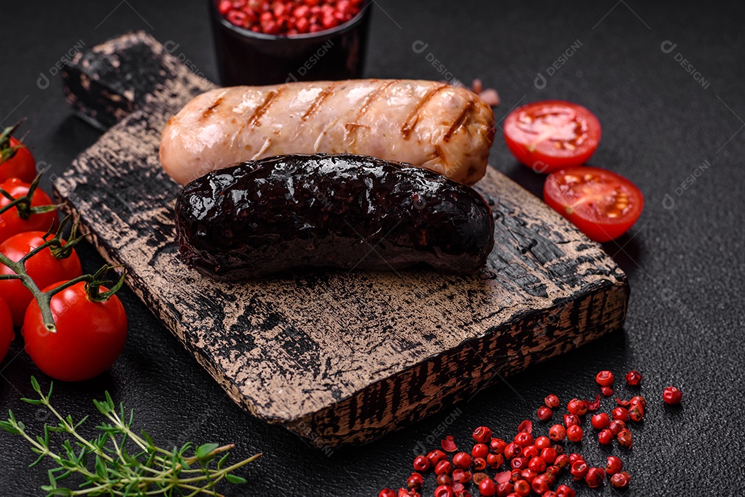 Deliciosas salsichas suculentas de diversas variedades grelhadas com sal, especiarias e ervas sobre um fundo escuro de concreto