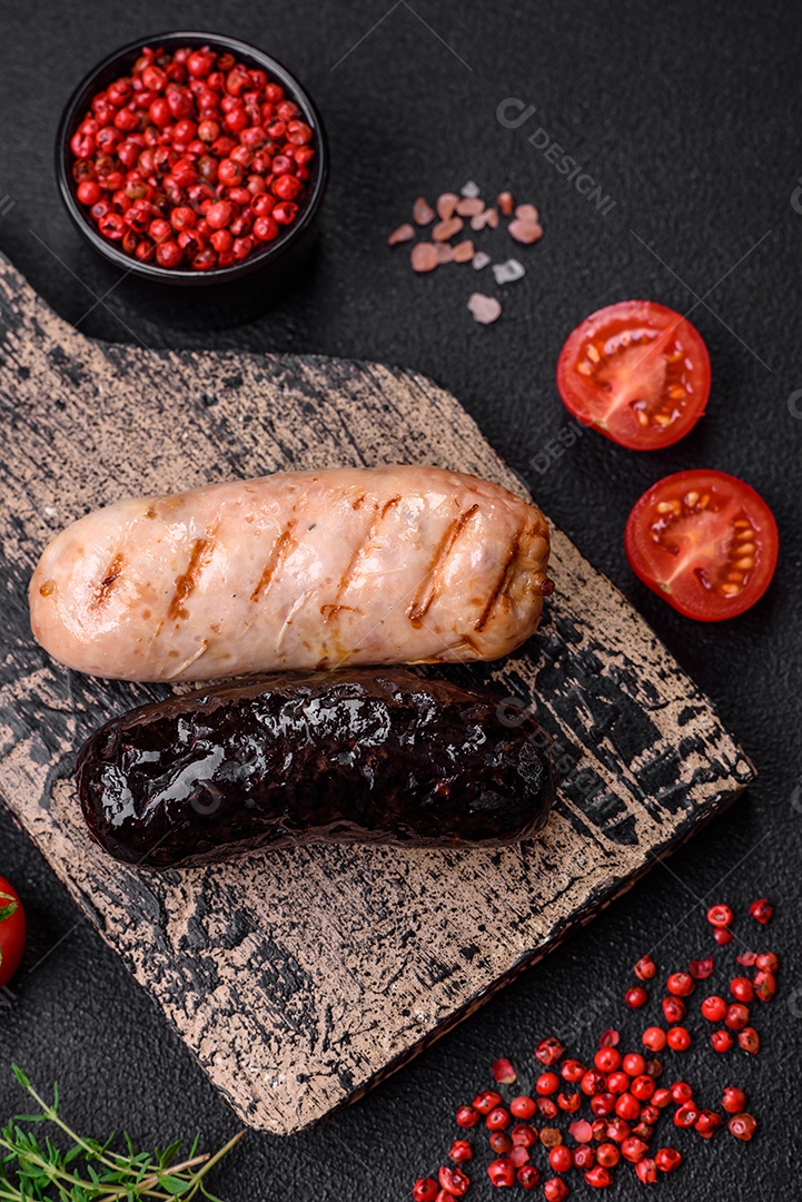 Deliciosas salsichas suculentas de diversas variedades grelhadas com sal, especiarias e ervas sobre um fundo escuro de concreto