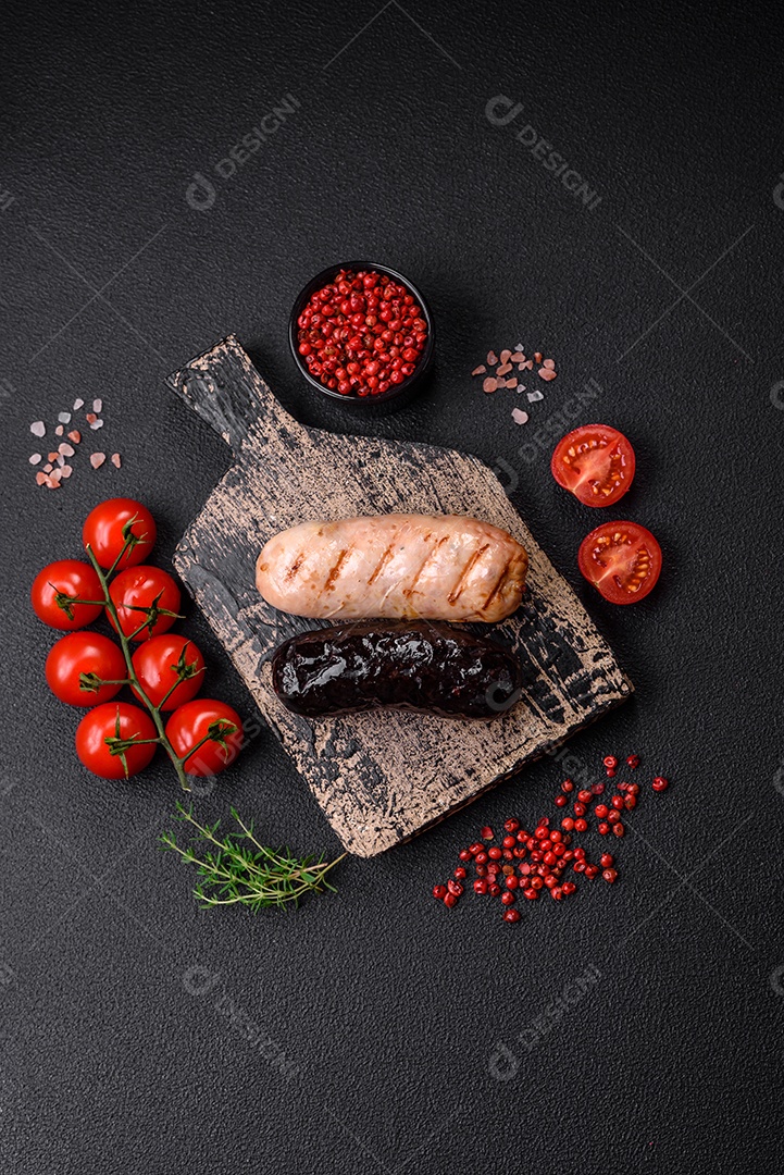 Deliciosas salsichas suculentas de diversas variedades grelhadas com sal, especiarias e ervas sobre um fundo escuro de concreto