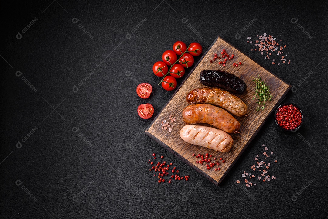 Deliciosas salsichas suculentas de diversas variedades grelhadas com sal, especiarias e ervas sobre um fundo escuro de concreto