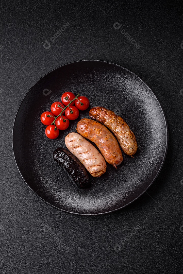 Deliciosas salsichas suculentas de diversas variedades grelhadas com sal, especiarias e ervas sobre um fundo escuro de concreto