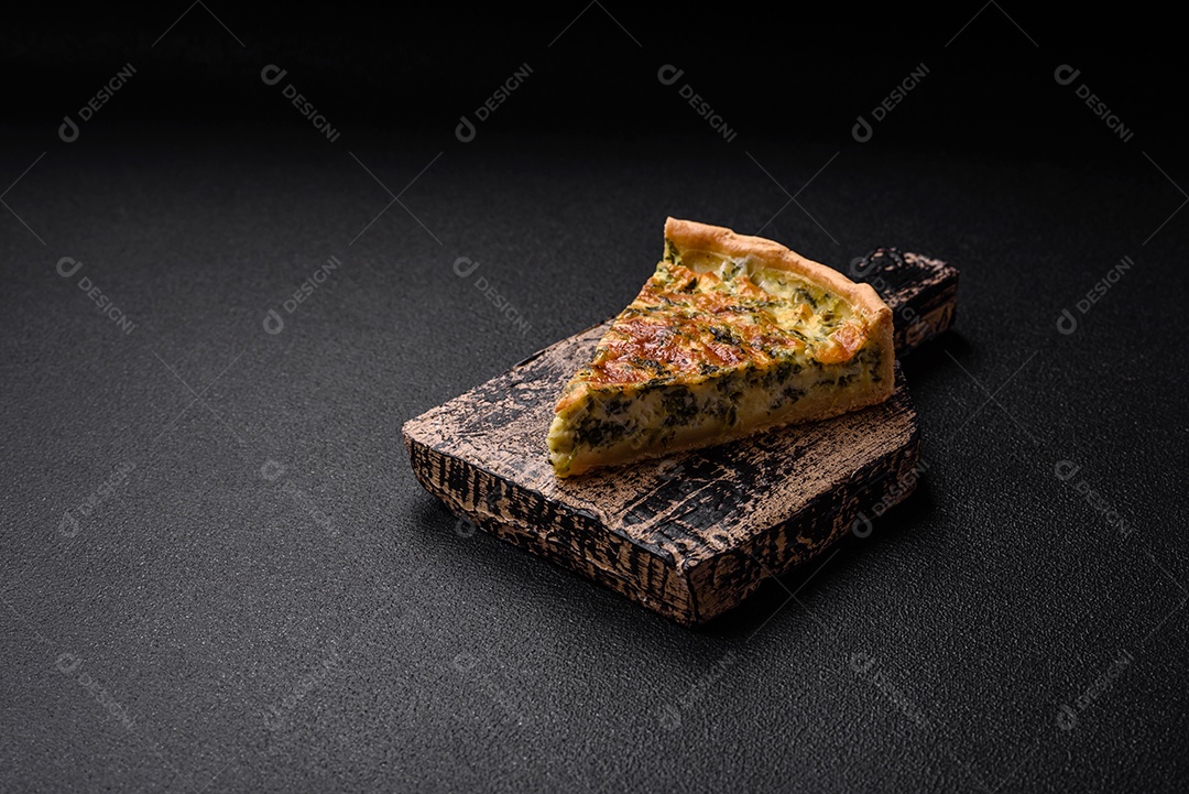 Deliciosa quiche fresca com brócolis, queijo, especiarias e ervas cortadas em pedaços sobre um fundo escuro de concreto