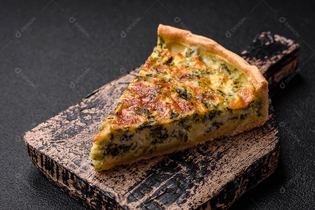 Deliciosa quiche fresca com brócolis, queijo, especiarias e ervas cortadas em pedaços sobre um fundo escuro de concreto