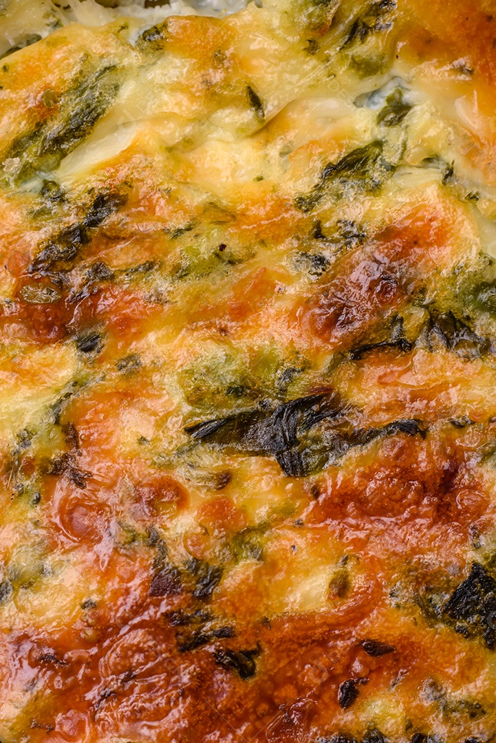 Deliciosa quiche fresca com brócolis, queijo, especiarias e ervas cortadas em pedaços sobre um fundo escuro de concreto