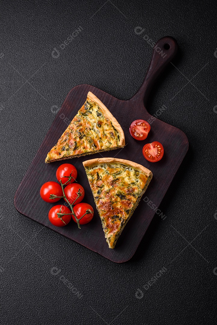 Deliciosa quiche fresca com brócolis, queijo, especiarias e ervas cortadas em pedaços sobre um fundo escuro de concreto