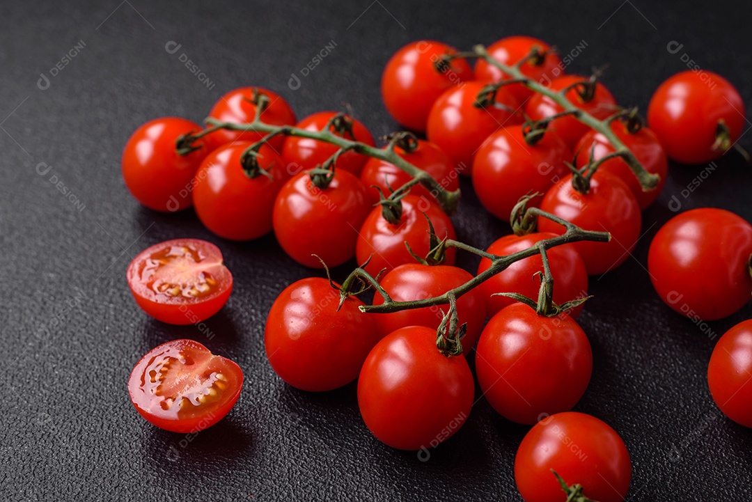 Deliciosos tomates cereja frescos nos galhos como ingrediente para cozinhar um prato vegetariano sobre um fundo escuro de concreto
