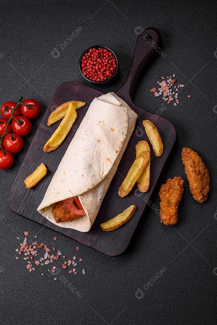 Delicioso rolo com nuggets de frango, tomate, alface e molhos com sal e especiarias sobre fundo escuro de concreto