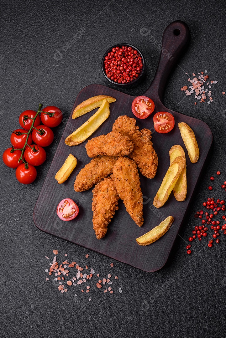Deliciosos nuggets de frango crocantes à milanesa com sal e especiarias sobre um fundo escuro de concreto
