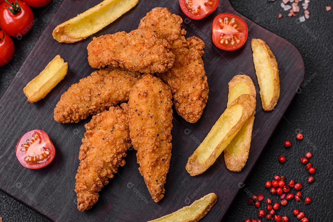 Deliciosos nuggets de frango crocantes à milanesa com sal e especiarias sobre um fundo escuro de concreto