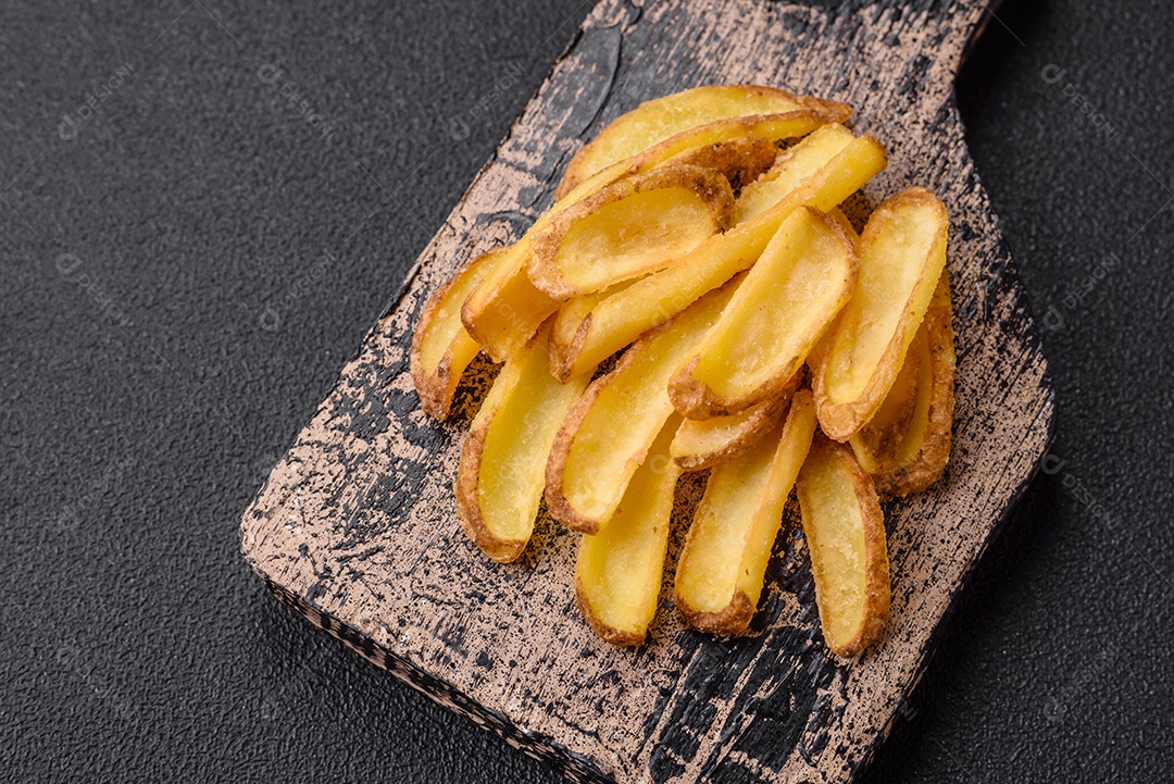 Deliciosas batatas crocantes com sal e especiarias em um fundo de concreto texturizado. Comida rápida