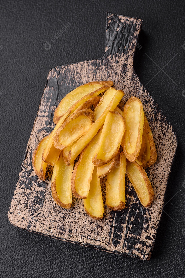 Deliciosas batatas crocantes com sal e especiarias em um fundo de concreto texturizado. Comida rápida