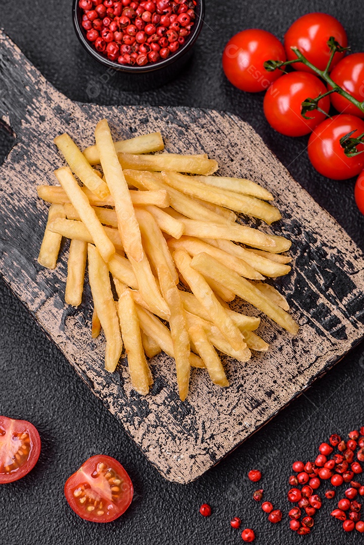Deliciosas batatas fritas crocantes com sal e especiarias em um fundo de concreto texturizado. Comida rápida