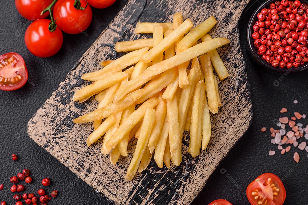 Deliciosas batatas fritas crocantes com sal e especiarias em um fundo de concreto texturizado. Comida rápida