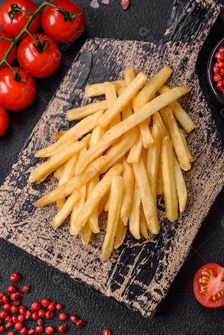 Deliciosas batatas fritas crocantes com sal e especiarias em um fundo de concreto texturizado. Comida rápida