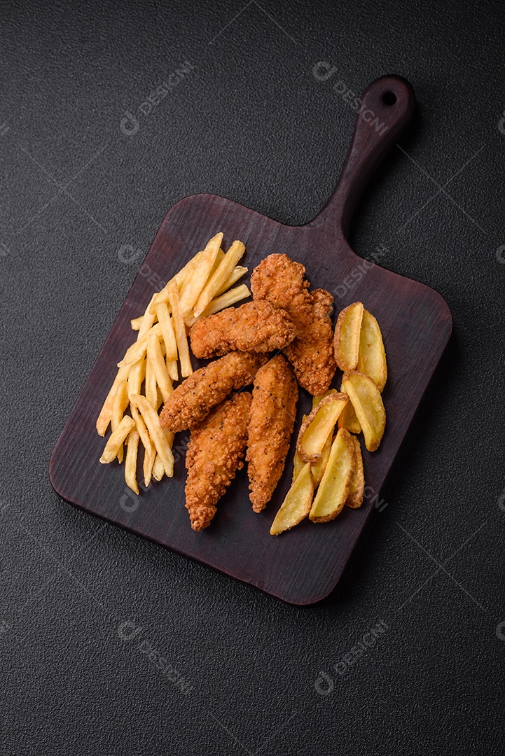 Deliciosos nuggets de frango crocantes à milanesa com sal e especiarias sobre um fundo escuro de concreto