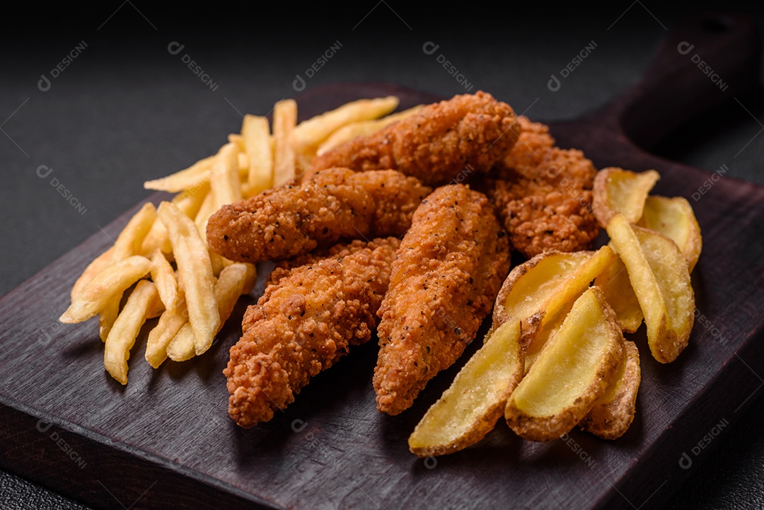 Deliciosos nuggets de frango crocantes à milanesa com sal e especiarias sobre um fundo escuro de concreto