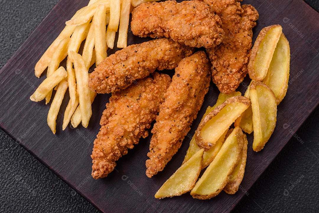 Deliciosos nuggets de frango crocantes à milanesa com sal e especiarias sobre um fundo escuro de concreto