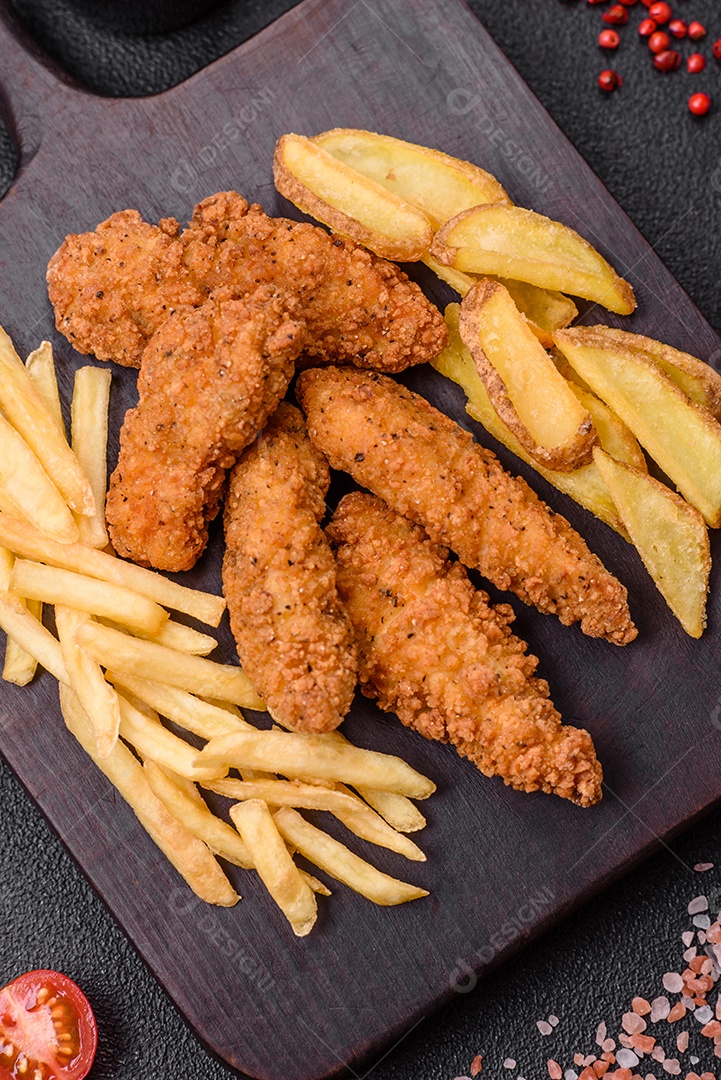 Deliciosos nuggets de frango crocantes à milanesa com sal e especiarias sobre um fundo escuro de concreto