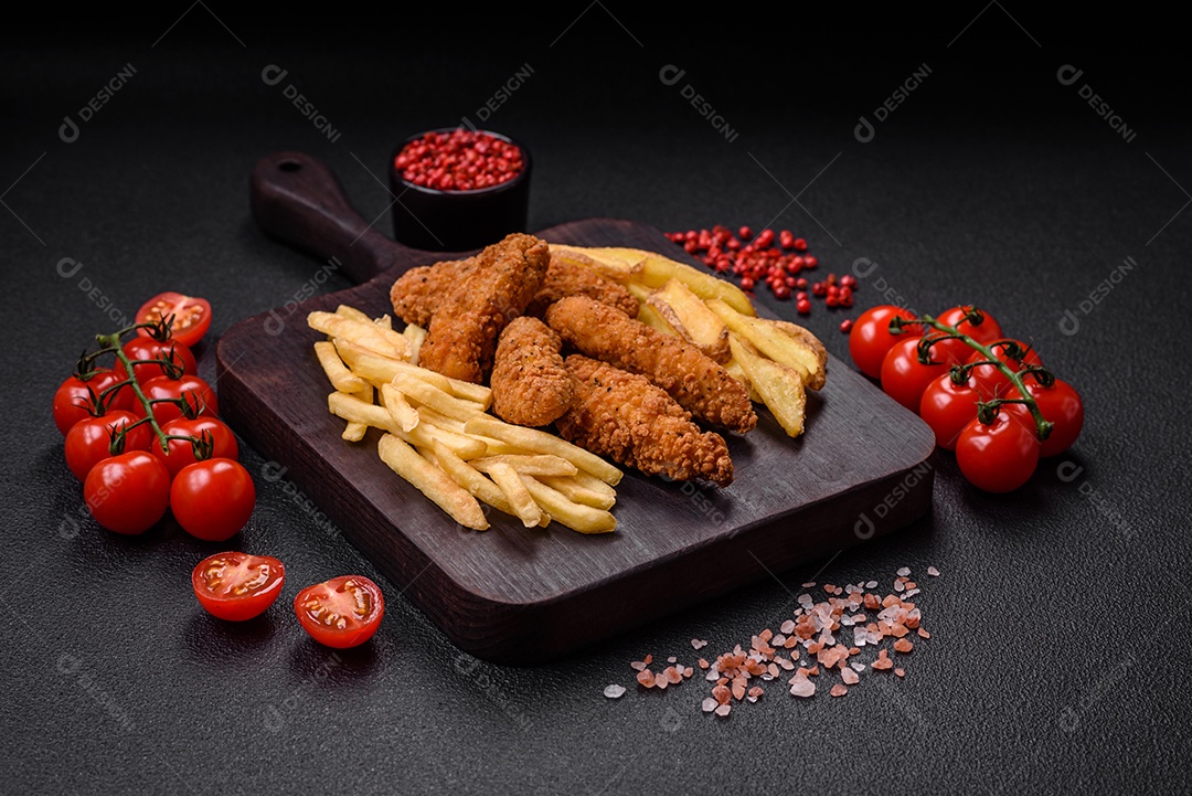 Deliciosos nuggets de frango crocantes à milanesa com sal e especiarias sobre um fundo escuro de concreto