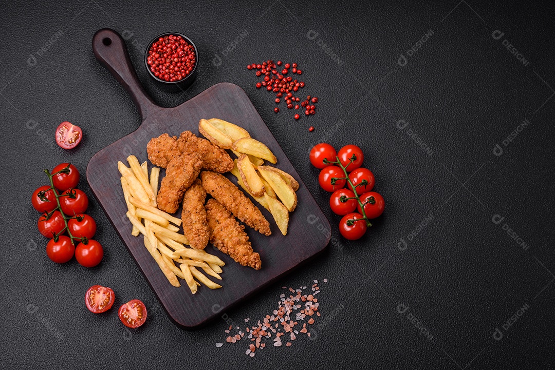 Deliciosos nuggets de frango crocantes à milanesa com sal e especiarias sobre um fundo escuro de concreto