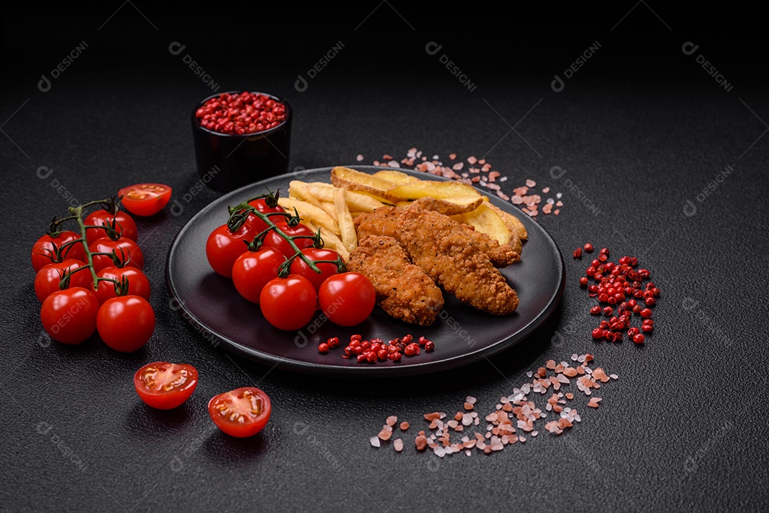 Deliciosos nuggets de frango crocantes à milanesa com sal e especiarias sobre um fundo escuro de concreto