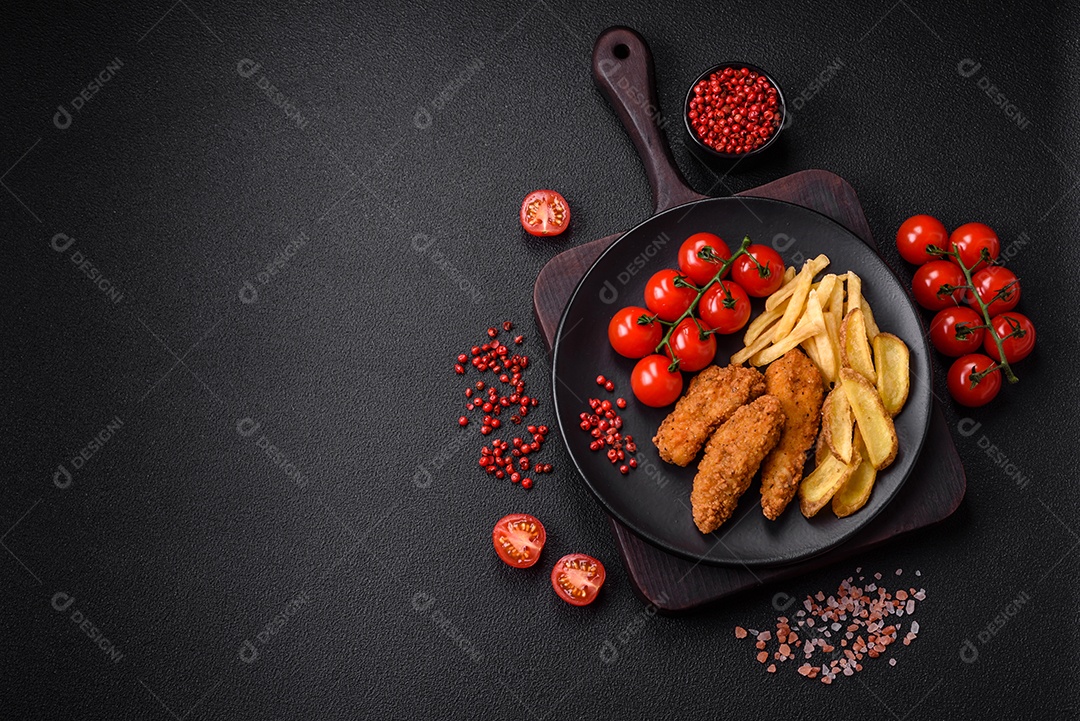 Deliciosos nuggets de frango crocantes à milanesa com sal e especiarias sobre um fundo escuro de concreto