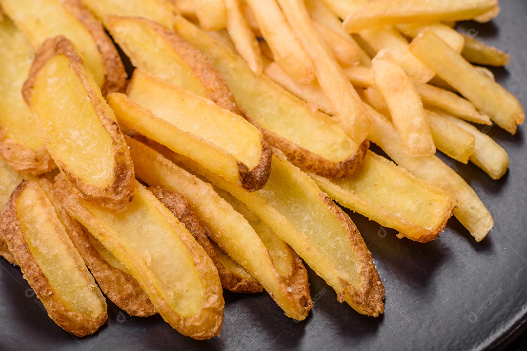 Deliciosas batatas fritas crocantes com sal e especiarias em um fundo de concreto texturizado. Comida rápida