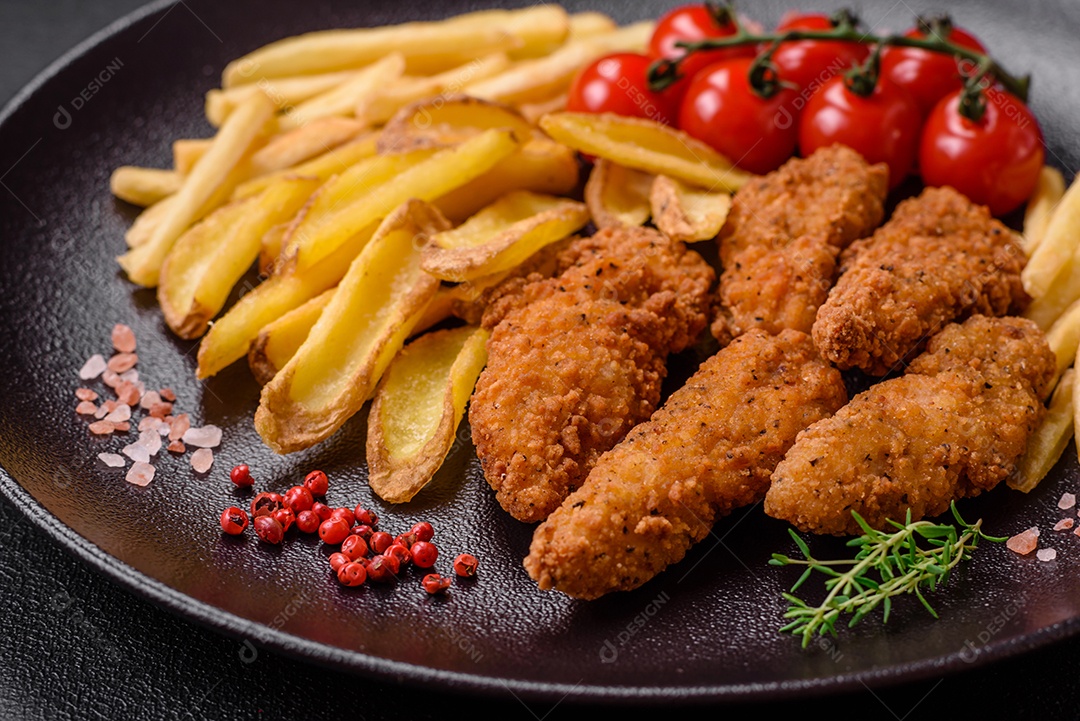 Deliciosos nuggets de frango crocantes à milanesa com sal e especiarias sobre um fundo escuro de concreto