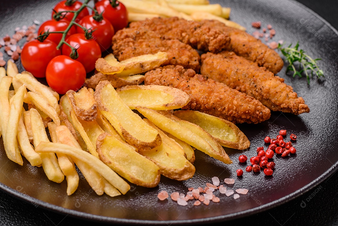Deliciosos nuggets de frango crocantes à milanesa com sal e especiarias sobre um fundo escuro de concreto
