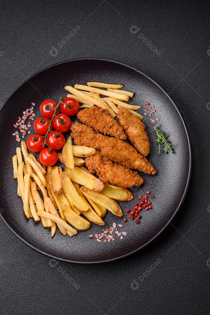 Deliciosos nuggets de frango crocantes à milanesa com sal e especiarias sobre um fundo escuro de concreto