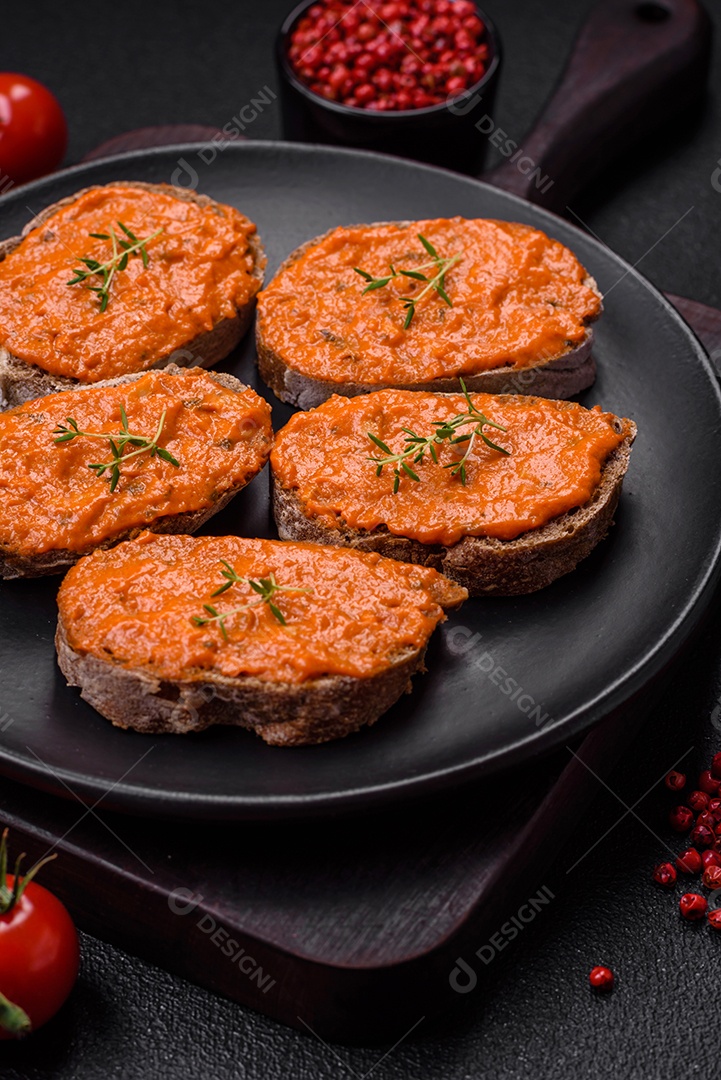 Delicioso sanduíche composto por torradas, molho vermelho com sal, especiarias e ervas sobre um fundo escuro de concreto