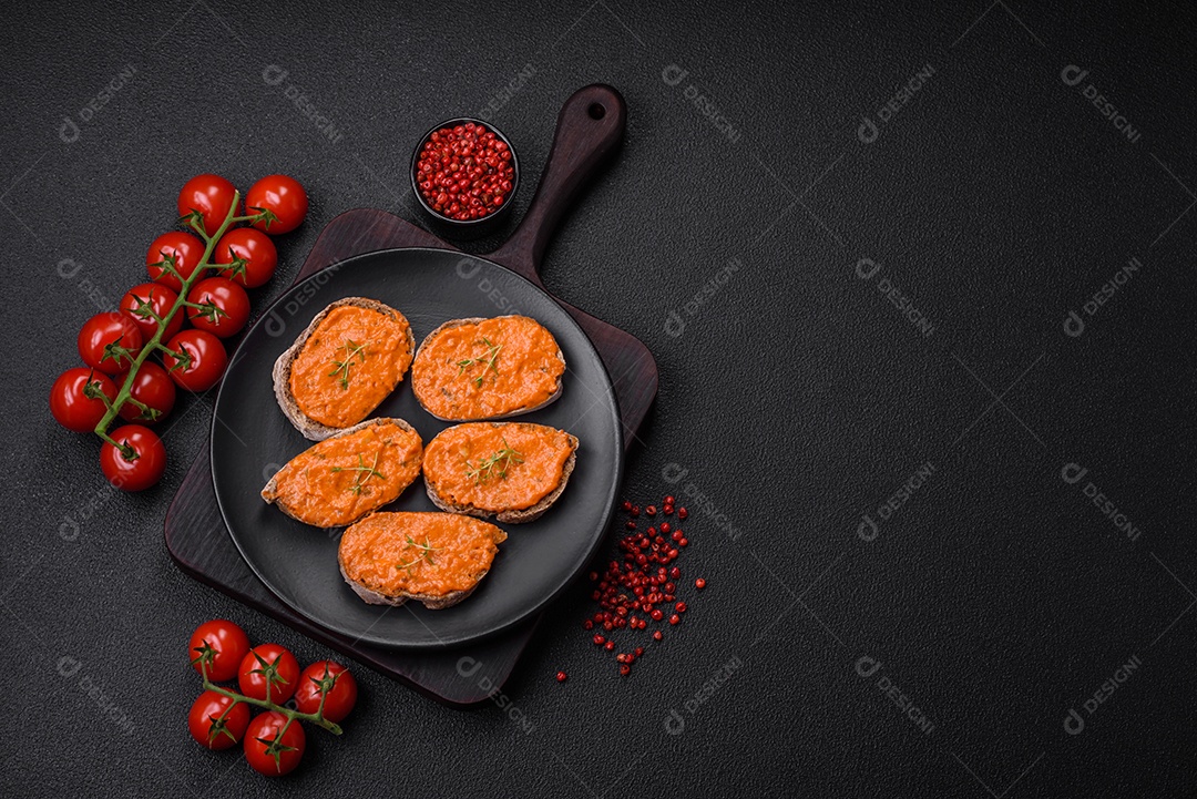 Delicioso sanduíche composto por torradas, molho vermelho com sal, especiarias e ervas sobre um fundo escuro de concreto