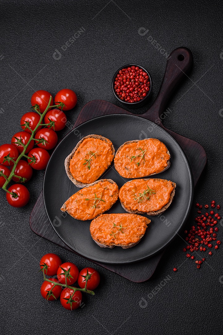 Delicioso sanduíche composto por torradas, molho vermelho com sal, especiarias e ervas sobre um fundo escuro de concreto