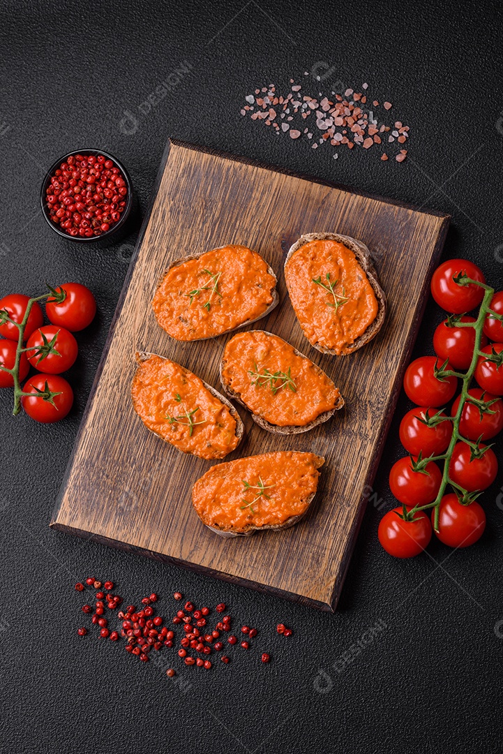 Delicioso sanduíche composto por torradas, molho vermelho com sal, especiarias e ervas sobre um fundo escuro de concreto