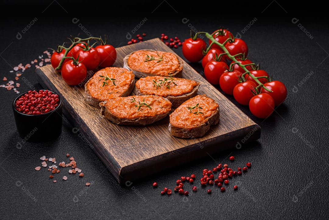 Delicioso sanduíche composto por torradas, molho vermelho com sal, especiarias e ervas sobre um fundo escuro de concreto