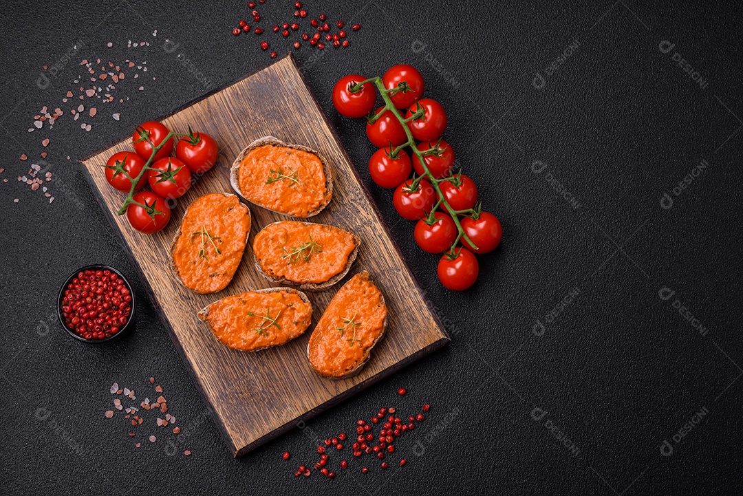 Delicioso sanduíche composto por torradas, molho vermelho com sal, especiarias e ervas sobre um fundo escuro de concreto