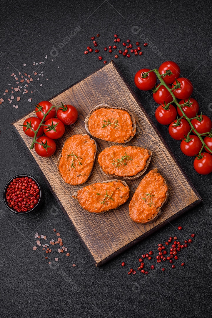 Delicioso sanduíche composto por torradas, molho vermelho com sal, especiarias e ervas sobre um fundo escuro de concreto