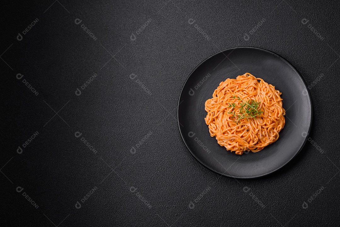 Deliciosa massa fresca composta por macarrão fino, molho pesto rosso vermelho com sal, especiarias e ervas sobre um fundo escuro de concreto