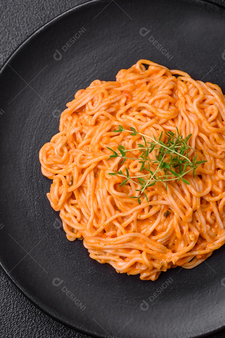 Deliciosa massa fresca composta por macarrão fino, molho pesto rosso vermelho com sal, especiarias e ervas sobre um fundo escuro de concreto