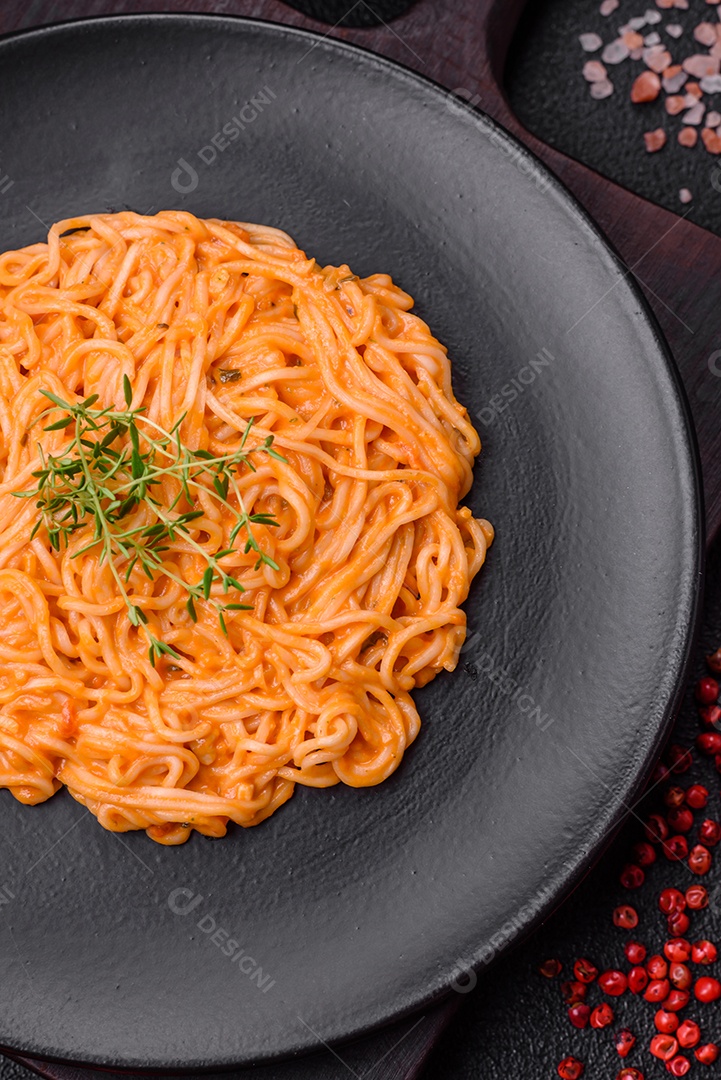 Deliciosa massa fresca composta por macarrão fino, molho pesto rosso vermelho com sal, especiarias e ervas sobre um fundo escuro de concreto