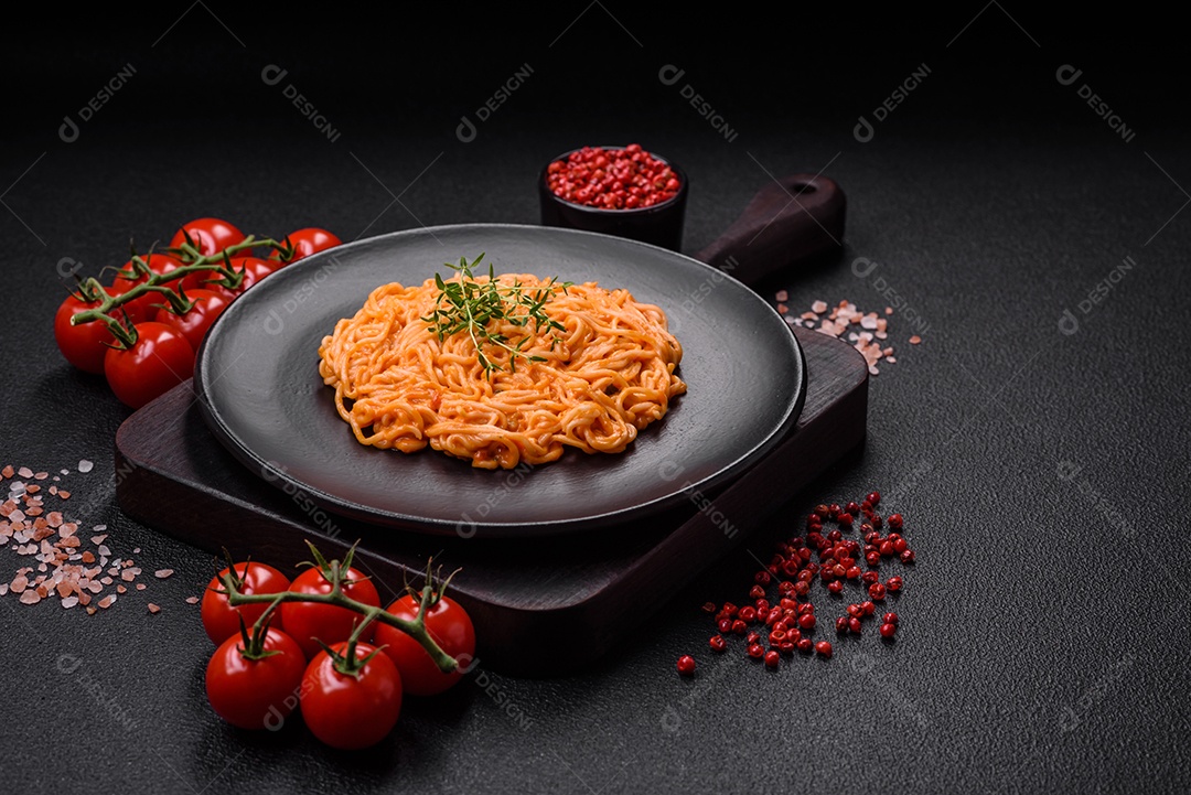 Deliciosa massa fresca composta por macarrão fino, molho pesto rosso vermelho com sal, especiarias e ervas sobre um fundo escuro de concreto