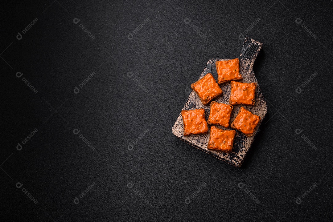 Delicioso sanduíche composto por torradas, molho vermelho com sal, especiarias e ervas sobre um fundo escuro de concreto