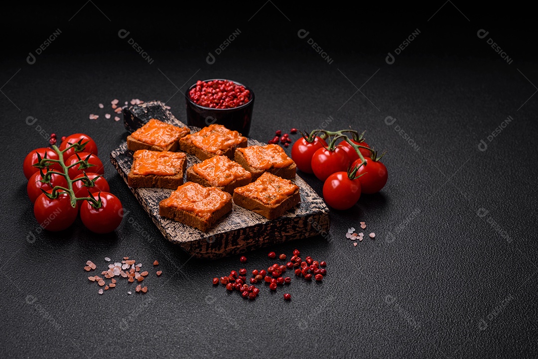 Delicioso sanduíche composto por torradas, molho vermelho com sal, especiarias e ervas sobre um fundo escuro de concreto