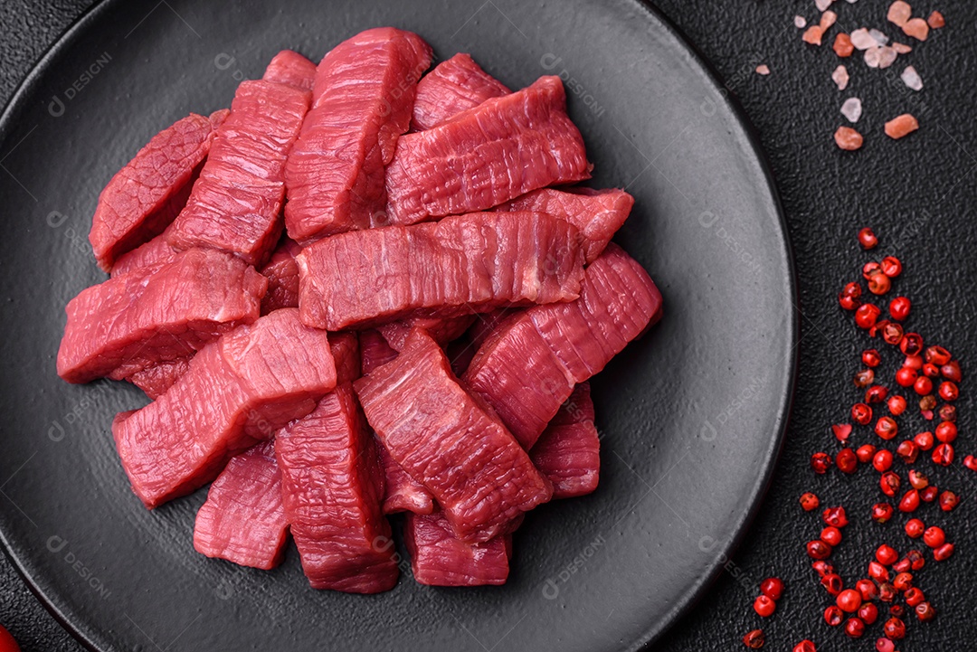 Carne crua fresca e suculenta com sal, especiarias e ervas sobre um fundo de concreto texturizado escuro