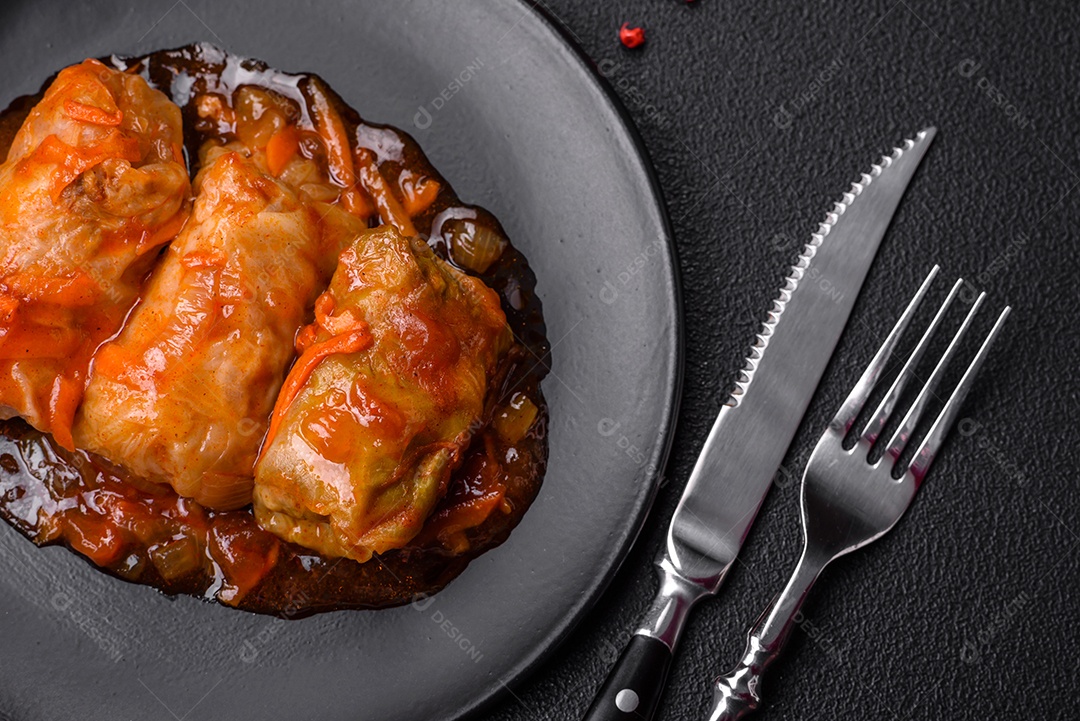 Delicioso dolma em molho de tomate com cenoura, cebola, sal, especiarias e ervas sobre um fundo escuro de concreto