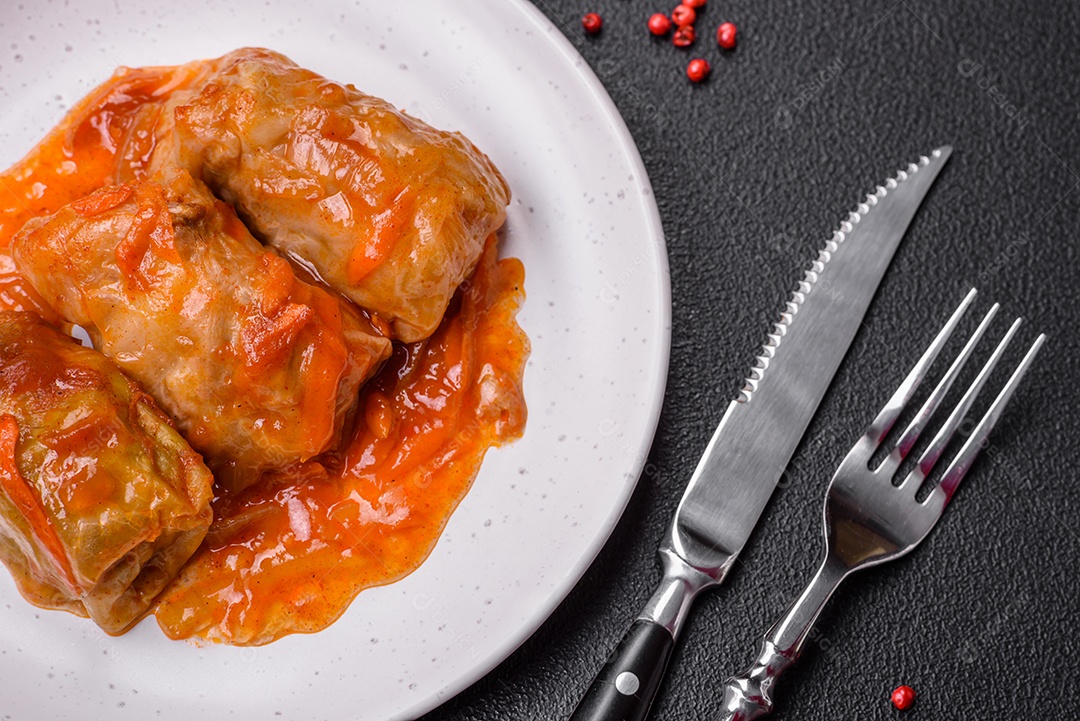Delicioso dolma em molho de tomate com cenoura, cebola, sal, especiarias e ervas sobre um fundo escuro de concreto