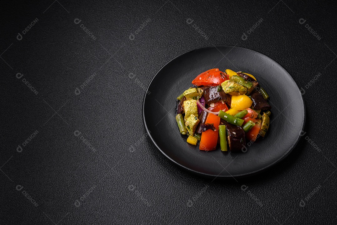 Deliciosa salada fresca e suculenta de berinjela assada, tomate, abobrinha, cebola, especiarias e sal sobre um fundo escuro de concreto