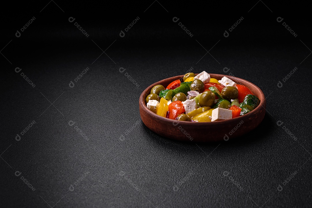 Deliciosa salada grega fresca e suculenta com queijo feta, azeitonas, tomates, pepino, pimenta, sal e especiarias sobre um fundo escuro de concreto