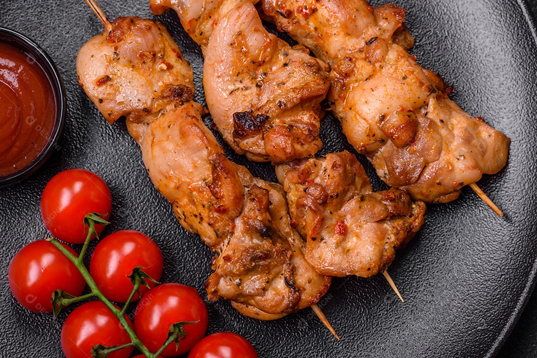 Delicioso frango fresco e suculento ou kebab de porco em espetos com sal e especiarias sobre um fundo escuro de concreto