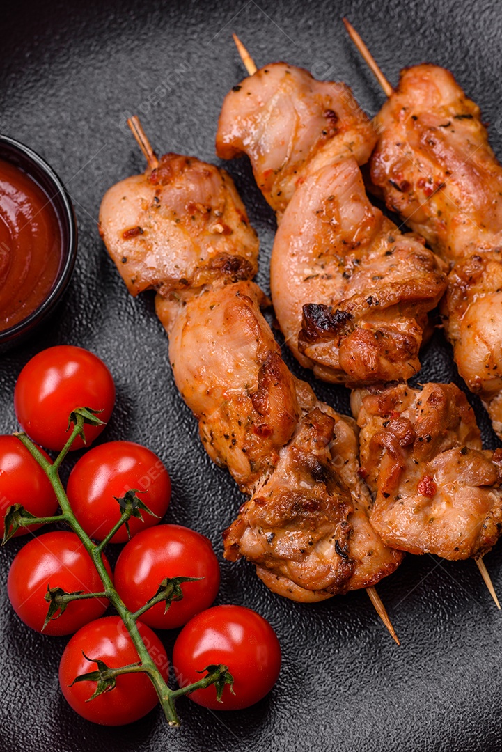 Delicioso frango fresco e suculento ou kebab de porco em espetos com sal e especiarias sobre um fundo escuro de concreto